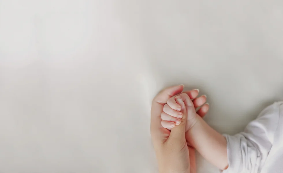 Matka trzyma rączkę dziecka na znak opieki