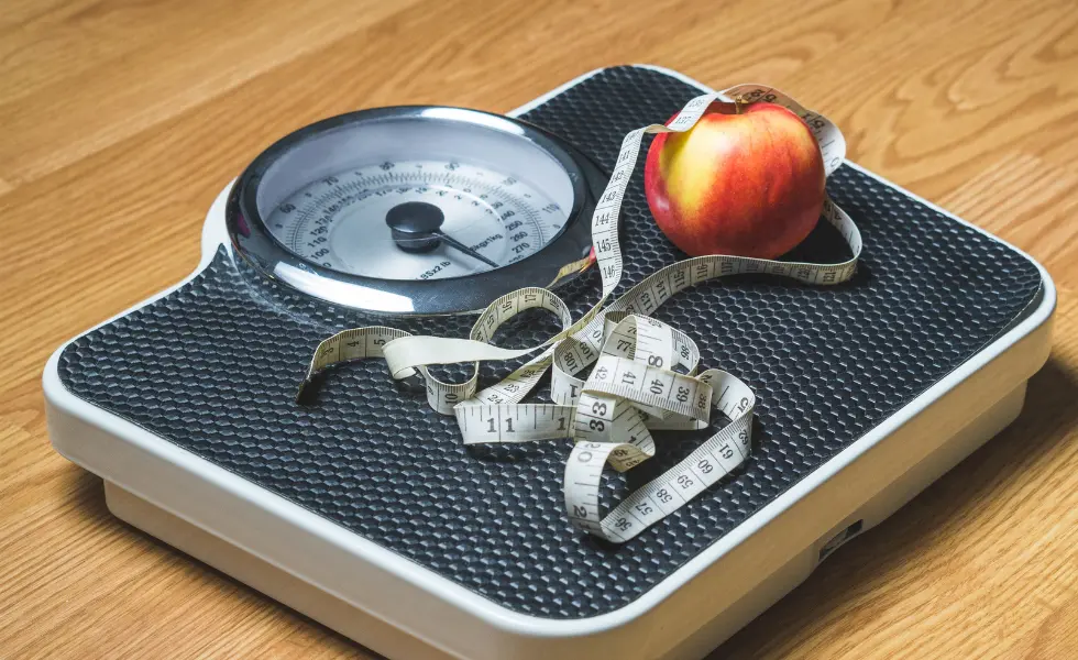 Jabłko z miarką krawiecką na wadze jako przenośnia do ważenia się 