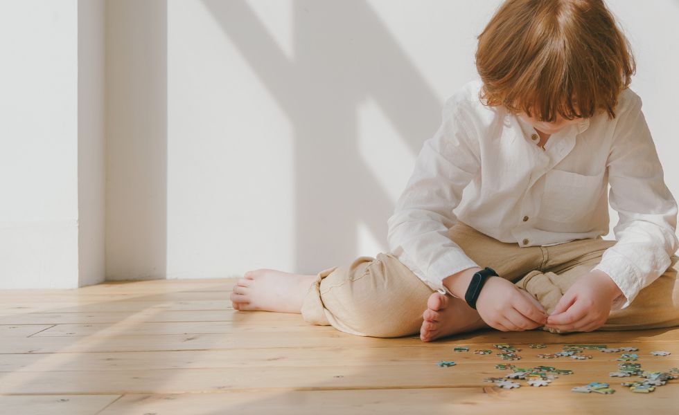 Smutne dziecko siedzi samo i układa puzzle