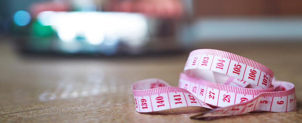 ważąca się osoba a na pierwszym planie miarka krawiecka